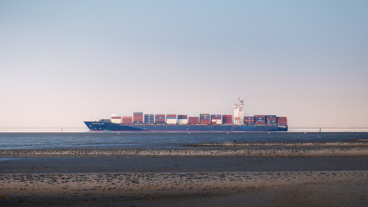 Container ship sailing near Cuxhaven, Germany, on a tranquil day.