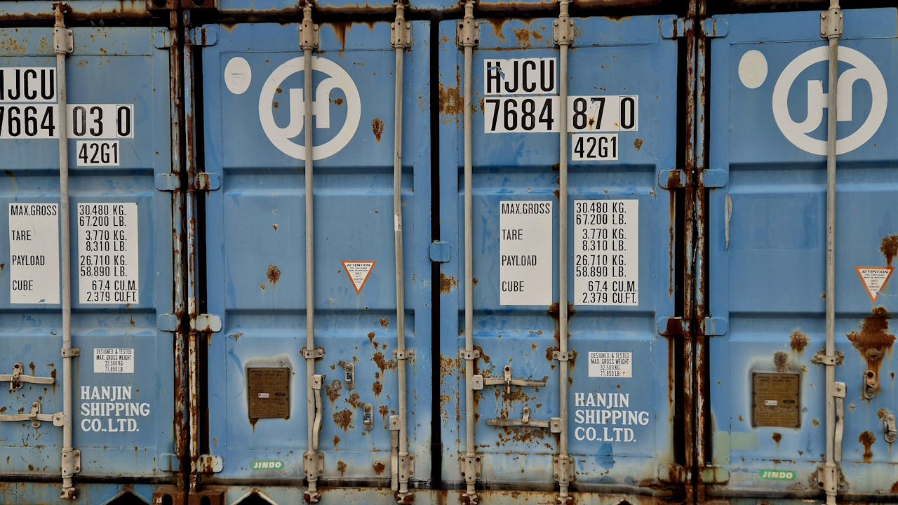 Close-up of a rusted blue Hanjin shipping container displaying weight and size information.